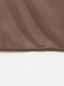 Détail macro d'un tissu en maille marron de qualité avec couture de surjet précise sur le bord