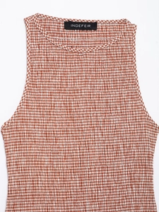 Detail of red and white gingham fabric with elasticated smocked texture and neckline tag