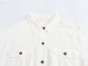 Detailed close-up of white cotton linen midi dress with marble buttons and flap pockets