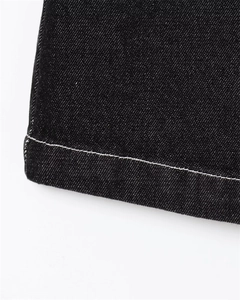 Macro detail of black twill denim fabric with white contrast stitching on the edge