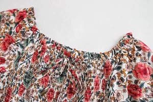 Dettaglio dello scollo di un abito a fiori rossi con punto smock e lacci regolabili