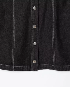 Close-up of black denim dress with silver metal buttons and white contrast stitching detail