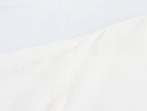 Close-up of premium cotton linen fabric texture and stitching on white midi shirt dress