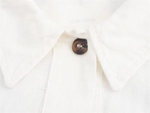 Detail of white cotton linen shirt collar with dark brown tortoise shell button texture