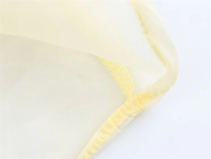 Gros plan détaillé des coutures sur le tissu transparent jaune de la jupe à volants