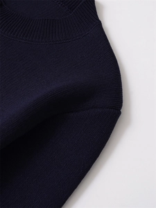 Détail macro du cardigan en maille bleu marine avec col côtelé et texture fine