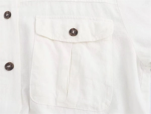 Detailed close-up of white cotton linen midi dress with cargo pocket and amber button