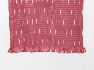 Détail du tissu smocké rose poudré avec imprimé blanc et bordure à volants