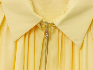 Détail du col d'un blouson aviateur jaune avec tirette dorée rétro en blason