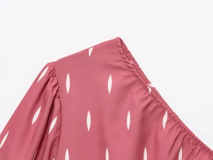 Gros plan sur les manches bouffantes roses et l'imprimé gouttes blanches de la robe
