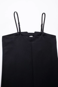 Détail du décolleté de robe noire à fines bretelles réglables et découpe en métal