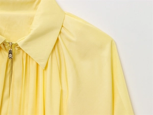 Vue détaillée d'une fermeture éclair dorée gravée sur une veste aviateur jaune clair