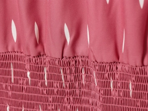 Gros plan détaillé du corsage élastique froncé avec imprimé feuilles blanches sur robe rose