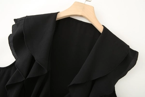 Détail de volants en mousseline noire et tissu texturé sur un haut élégant sans manches
