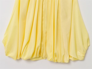 Vue détaillée de l'ourlet en satin jaune avec texture bouffante de la veste