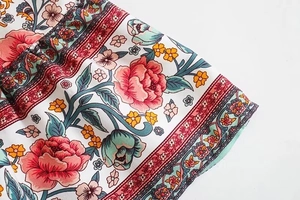 Dettaglio del tessuto con stampa floreale boho con peonie rosa e bordo decorato