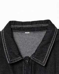 Detail of black denim collar with contrast white stitching and silver metal button