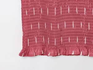 Détail du tissu smocké rose avec rayures blanches et bordure à volants froncés