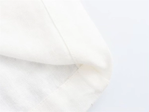 Detail of white cotton-linen shirt dress showing fine rolled hem sewing and fabric texture
