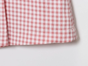 Gros plan sur le tissu seersucker à carreaux rose et blanc avec ourlet soigné