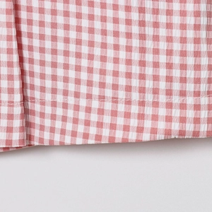 Gros plan sur le tissu seersucker à carreaux vichy rouges avec détails de couture