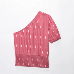 Haut rose à une épaule avec motifs navette blancs et taille élastiquée