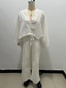 Détail d'un ensemble deux pièces blanc en lin avec col en V, ourlet à cordon et pantalon large