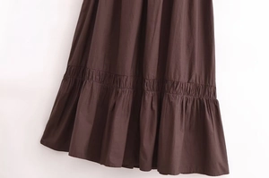 Detailed close-up of dark brown tiered dress hem with ruffled layers and cotton texture