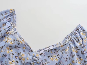 Détail de l'encolure en V plissée et de l'imprimé floral délicat sur ce tissu bleu