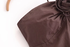 Detail of dark brown halter dress featuring 3D floral rosettes and premium matte fabric