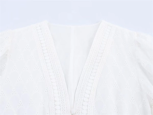 Detailed close-up of V-neckline with delicate embroidery and button on lace dress