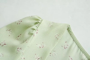 Detail eines hellgrünen Blumenkleides mit Puffärmelfalten und sauberer Verarbeitung