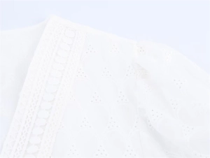 Detail of white Broderie Anglaise blouse featuring lace trim and intricate embroidery