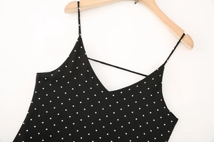 Detail of the V-neck with criss-cross straps on a black polka dot sleeveless dress