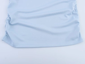 Détail de la robe en maille bleu clair avec fronces latérales et ourlet bien fini