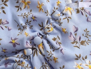 Détail d'une robe en viscose à fleurs avec boutons recouverts et texture plissée