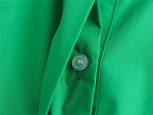 Makrodetail von smaragdgrünem Baumwollgewebe und weißer Knopfarbeit an diesem Hemdkleid