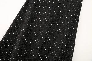 Close-up of black and white polka dot fabric with woven diagonal texture and soft drape