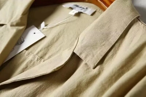 Close-up of linen jumpsuit collar with size M tag and neat stitching details