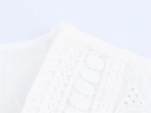 Detailed close-up of intricate white lace embroidery and hollow-out patterns on the dress