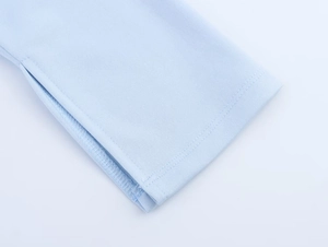 Gros plan sur un tricot bleu clair avec fente latérale et coutures à double aiguille