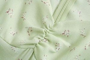 Detail von hellgrünem floralem Chiffon mit roten Drucken und verdecktem Reißverschluss