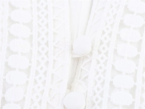 Detailed close-up of intricate white lace embroidery and fabric-covered button on dress