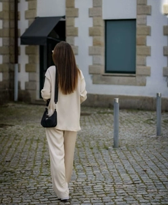 Detail view of a creamy white knitted two-piece set featuring long sleeves and trousers
