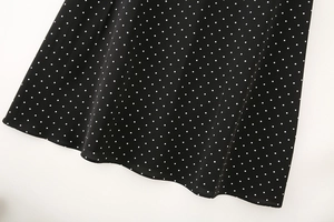 Close-up of black sleeveless dress hem with white polka dots on lightweight chiffon fabric