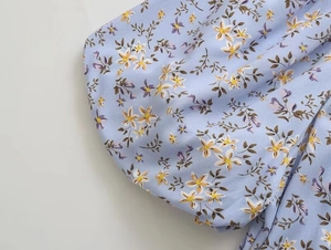 Détail d'une manche bouffante à fleurs avec imprimés bleus et violets sur tissu léger