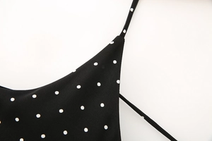 Detail of elegant black dress with white polka dots and narrow shoulder straps