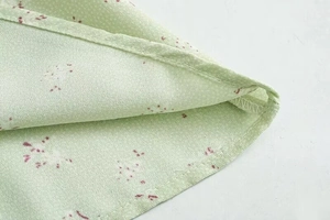 Detailaufnahme der feinen Nähte und des Rollsaums an diesem hellgrünen Blumenkleid