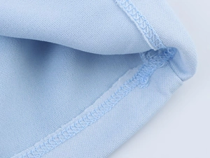 Gros plan sur l'ourlet en tissu bleu clair avec coutures nettes et texture fine
