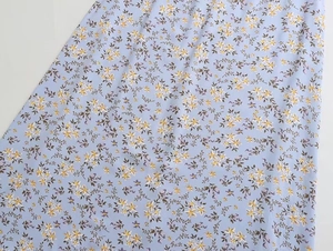 Détail du tissu sergé bleu clair avec de délicats motifs de fleurs jaunes et blanches